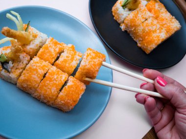 kadın el bir tabakta karides ile Sushi rulo alır