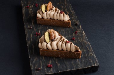 Koyu ahşap arka plan üzerinde ceviz fındık ve küçük çikolata topları ile dekore edilmiş çikolata mini tart