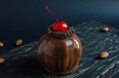 Siyah arka plan üzerinde kokteyl kiraz ve badem ile dekore edilmiş çikolata sır ile kaplı Kiraz mini mus kek