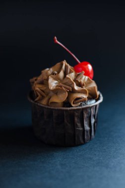 Siyah arka plan üzerinde kokteyl kiraz ile süslenmiş çikolata krema ile Çikolata cupcake