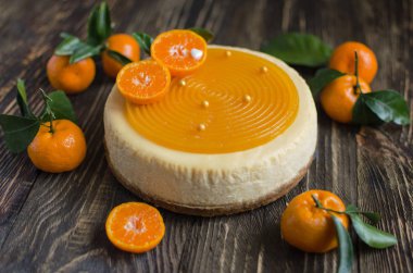 Ahşap arka planda taze mandalina ile dekore edilmiş meyveli cheesecake