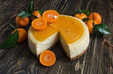 Ahşap arka planda taze mandalina ile dekore edilmiş meyveli cheesecake