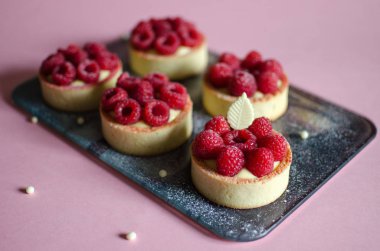 Pembe arka plan üzerinde çikolata elemanları ile dekore taze ahududu ile Mini tart