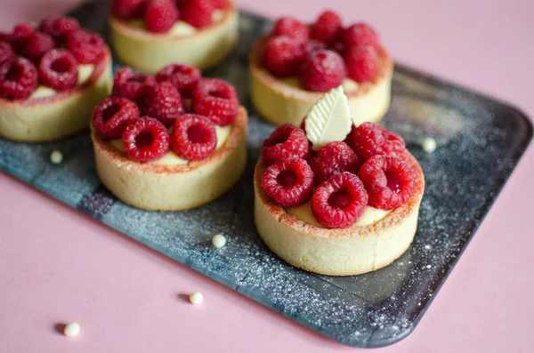 Pembe arka plan üzerinde çikolata elemanları ile dekore taze ahududu ile Mini tart