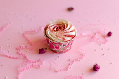 Pembe arka plan üzerinde krem peynir ile çilek Cupcake Rosebud ile süslenmiş