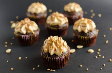 Fıstık kreması ve çikolata sosu ile çikolata cupcakes seti siyah arka plan üzerinde fıstık ile süslenmiş