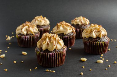 Fıstık kreması ve çikolata sosu ile çikolata cupcakes seti siyah arka plan üzerinde fıstık ile süslenmiş