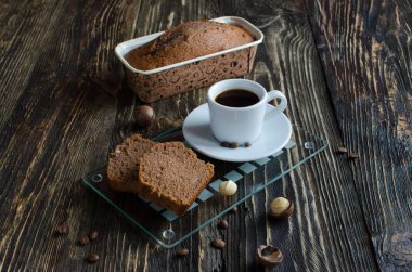 Koyu ahşap arka plan üzerinde macadamia fındık ve kahve fincan ile Kahve kek