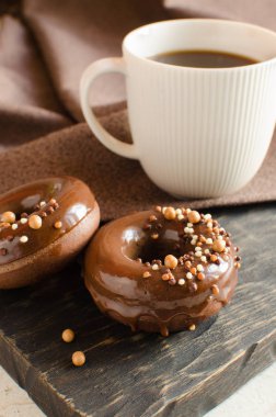 Koyu ahşap tahta üzerinde sır ve gevrek topları ile Çikolata donnuts