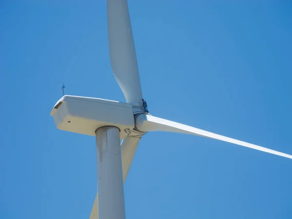 Wind Turbine with mechanic standing on blade