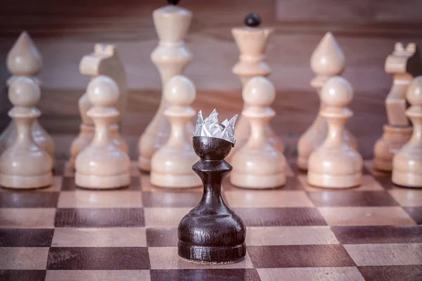 王冠立っている白の道の反対側の黒ポーンのチェス盤の数字します — ストック写真
