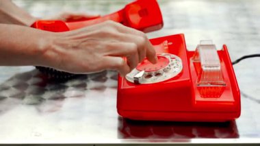 Masada, yan görünüm kırmızı antika döner telefon. Diğer el cihazı tutan iken el telefon numarasını çevirir. (telefonda tanınmaz logo zamanla yıpranmış ve bulanıklık bölgesinde bulunan).