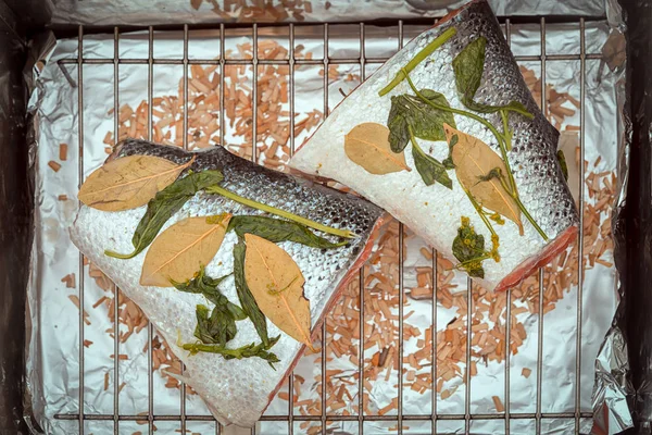 两个大片生鲑鱼与罗勒和月桂叶躺在一个熏制准备做饭的网格上 — 图库照片