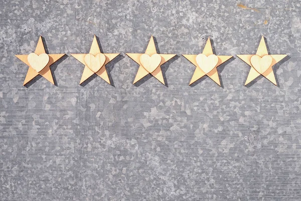 Five wooden stars and hearts on a tin-plate background with copy space. Concept of service rating and quality of trade with customer likes.