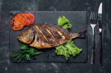 Siyah taş tepsi üzerinde ızgara dorada gıda üst görünümü servis.