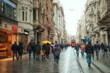 İstanbul, Türkiye - 14 Nisan 2019: İstanbul'un Europian kesiminde sokakta ki insanlar, İstikllal Bulvarı. Kırmızı nostaljik tramvay uzak avay. Yağmurlu gün.