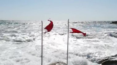 İki plaj uyarısı kırmızı bayraklar rüzgara sıçrayan. Fırtınalı deniz tehdit uyarısı. Tatil tehlikesi. Aşırı deniz suyu uyarısı.