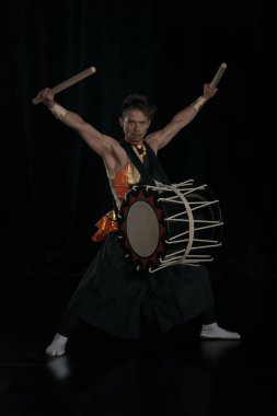 Siyah arka planda davul ve bagetlerle Taiko davulcusu
