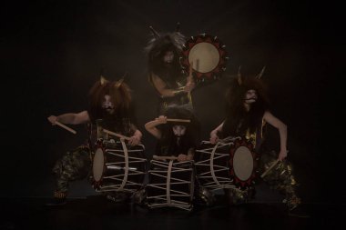 Japon mitolojisinden dört şeytan. Sahnede boynuzlu ve makyajlı sanatçı davulcuları Taiko 'nun tam uzunlukta portresi..