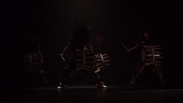 四人の芸術家は 暗い背景を背景に舞台上で角とメイクアップドラムを持つウィッグで太鼓を打ちます 日本神話の鬼 — ストック動画