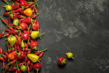 Siyah çimento masasının yanında kırmızı ve sarı kırmızı biberler ve acı biberler. Mutfak metnin için fotokopi alanı olan üst manzara..