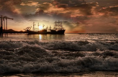 Gün doğumunda bir grup korsan yelkenli gemi.