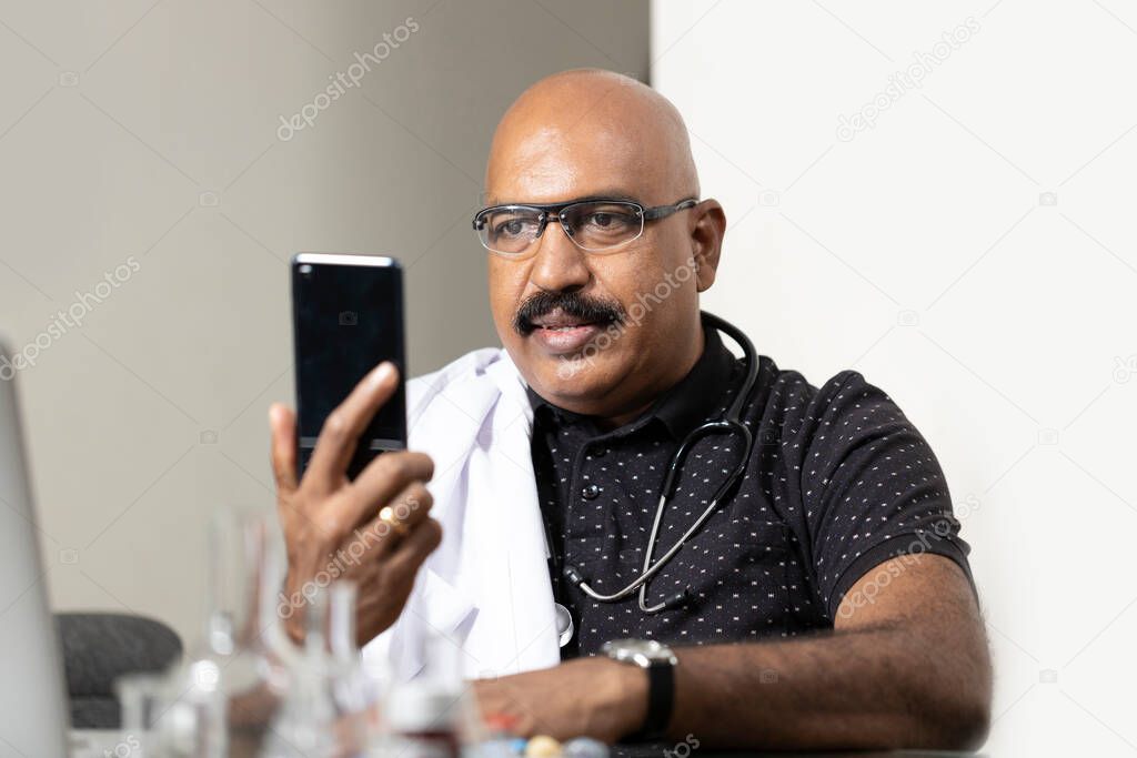 A doctor interacting with his patients through mobile phone as well as video conferencing