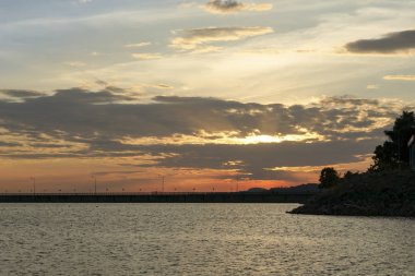 Barajda gün batımı su topluyor. Turuncu akşam gökyüzü