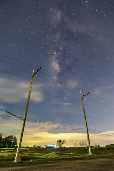 Gece kırsalında elektrik direkleri, yıldızlar ve güzel taro sahneleri ile gökyüzü, çim üzerinde ufuk altında bulutlar — Stok fotoğraf