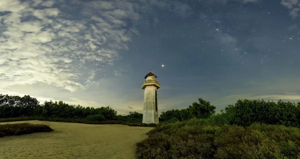 Deniz feneri denizde, vahşi doğada eski deniz feneri temiz görünüyor. Gökyüzünün arkasında bulutlar, yıldızlar ve Samanyolu var.. — Stok fotoğraf