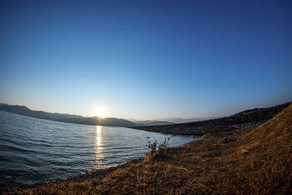 Sunrise at the reservoir, clear blue sky, wide angle from Lens F