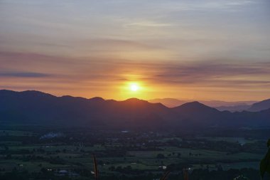 Dağın arkasında gün batımı, gökyüzü uzak bir dağ ya da