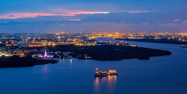 Street lights and street lighting from residential houses in the suburbs during sunset time, boat traffic on the Chao Phraya River, Samut Prakan, Thailand