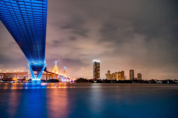 Purple led light under the bridge over the river On a cloudy day in the sky. Bhumibol Bridge, Samut Prakan, Thailand