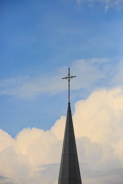 Aguja con una cruz en un edificio de una iglesia católica en el cielo — Foto de Stock