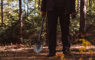 bir adam karanlık ormanda bir kürek almak