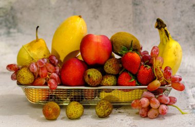 Metal sepetin içindeki egzotik meyveler beyaz üzerine izole edilmiş.