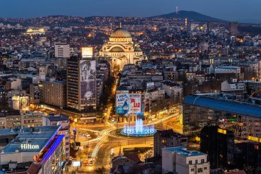 Belgrad, Sırbistan 31 Mart 2019: Gece Belgrad Panoraması. Saint Sava tapınağı, yeni çeşme, Hotel Slavija ve Slavija meydanı ile Belgrad şehir silueti.