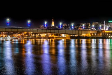 Belgrad, Sırbistan - 10 Şubat 2019: Belgrad'ın bir panoraması gece sava nehri kıyılarından yansımayla görülüyor. Brankov Köprüsü ve Başmelek Aziz Michael Katedrali'nin görünümü.