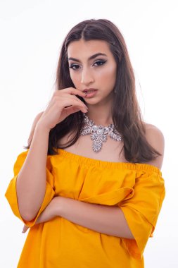 Çekici Genç Kadın Model Portresi. Kız beyaz bir arka plan ile bir stüdyoda sarı bir elbise ve takı ile poz.