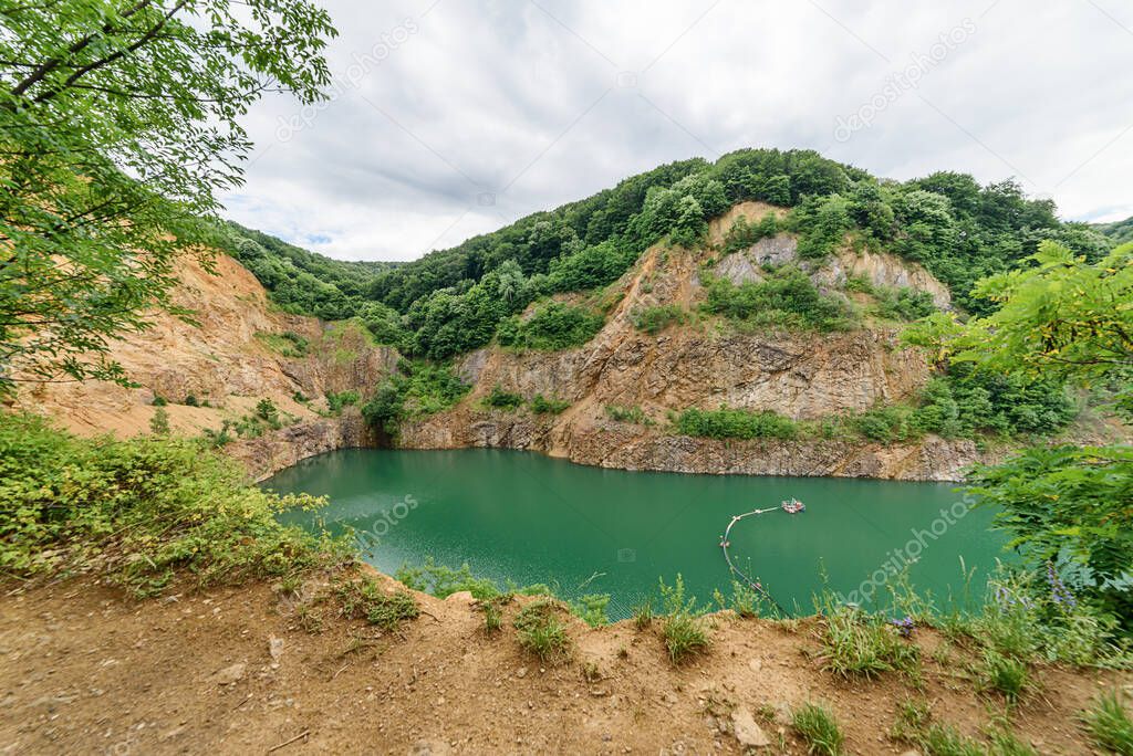 Beautiful Lake Ledinci (serbian: Ledinacko jezero) near Fruska Gora in Serbia, once there was a stone pit. Beautiful vibrant green deep mountain lake, hidden and surrounded by rocks and woods.