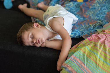 Yastıksız uyuyan bir çocuk televizyon seyrediyor.