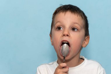 Küçük bir çocuk kaşığı yalıyor.