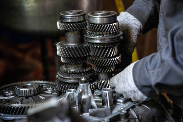A worker repairs a car's transmission, close-up