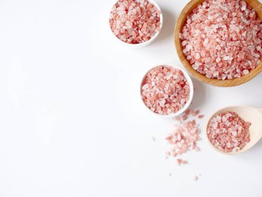 Spa yassı kompozisyonu. Tahta kavanozda deniz tuzu ve beyaz arka planda kaşığa dağılmış. Üst görünüm, telif alanı. Günlük bakım konsepti, rahatlama ve dinlenme, banyo prosedürü.