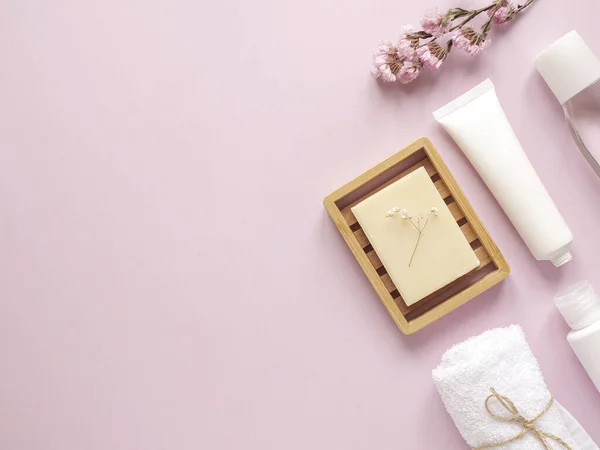 bakım ürünleri losyonu, krem, bitki, sabun, havlu. Pembe arka planda banyo aksesuarları, üst manzara, telif alanı. Ev konseptinde vücut bakımı güzellik tedavileri, organik ürünler, sabah rutini.