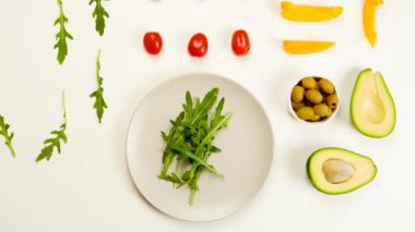 Salata için ayrıştırılmış malzeme beyaz arka planda tabakta taşınır. Sağlıklı, vejetaryen, vejetaryen ve organik. Yemek yumruklama. Hareket etme, düz yat, üst görünüm