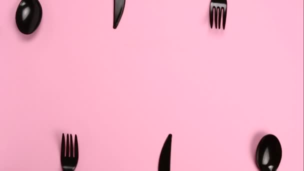 勺子和刀在停止运动时出现在粉色背景上 塑料餐具 塑料污染环境 一次性餐具 废物回收概念 — 图库视频影像