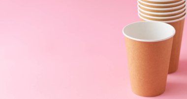 Pembe arka planda tek kullanımlık kağıt bardak. Ekoloji, plastik çevre kirliliği, atık geri dönüşümü kavramı. kopyalama alanı, pankart.