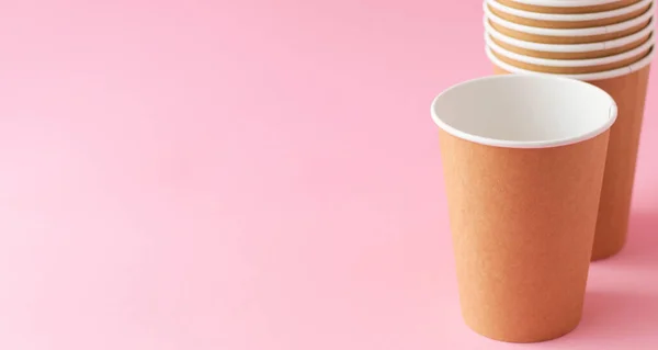 Pembe arka planda tek kullanımlık kağıt bardak. Ekoloji, plastik çevre kirliliği, atık geri dönüşümü kavramı. kopyalama alanı, pankart.